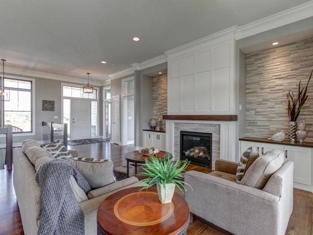 living area featuring recessed lighting, crown molding, wood finished floors, and a glass covered fireplace