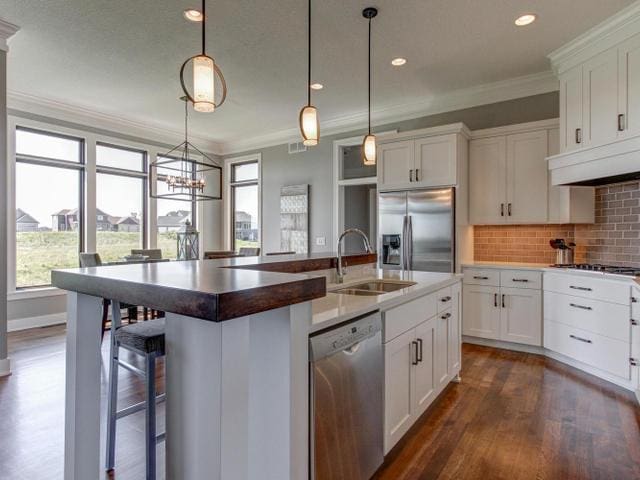 kitchen with ornamental molding, a sink, stainless steel appliances, and plenty of natural light