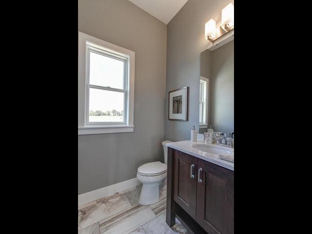 bathroom with toilet, vanity, and baseboards
