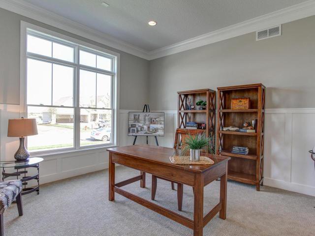 office area with a wainscoted wall, crown molding, light carpet, a decorative wall, and visible vents