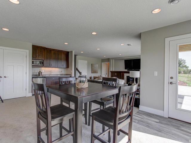 dining room with a textured ceiling, baseboards, bar, and recessed lighting