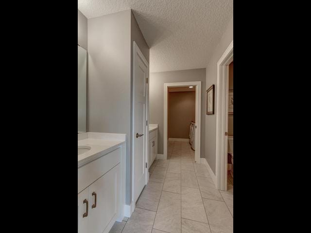 full bathroom with baseboards, vanity, and a textured ceiling