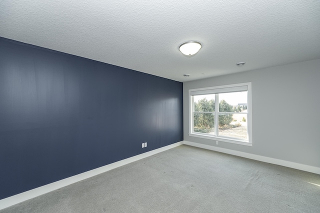 spare room featuring carpet, baseboards, and a textured ceiling