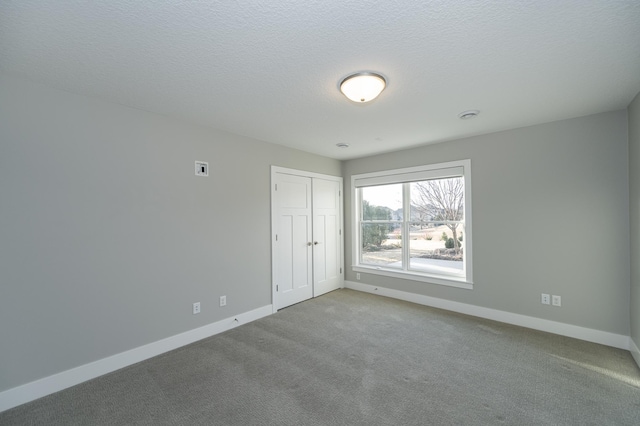 carpeted spare room featuring baseboards and a textured ceiling