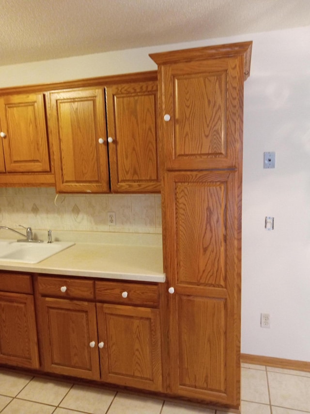 kitchen featuring sink, a textured ceiling, light tile patterned floors, and tasteful backsplash