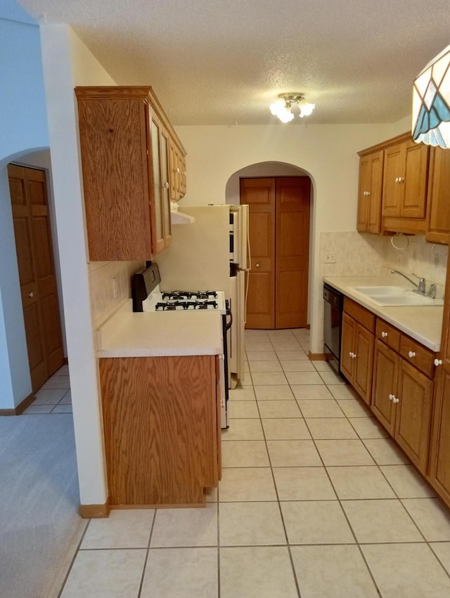 kitchen featuring a textured ceiling, dishwasher, range with gas stovetop, sink, and light tile patterned floors