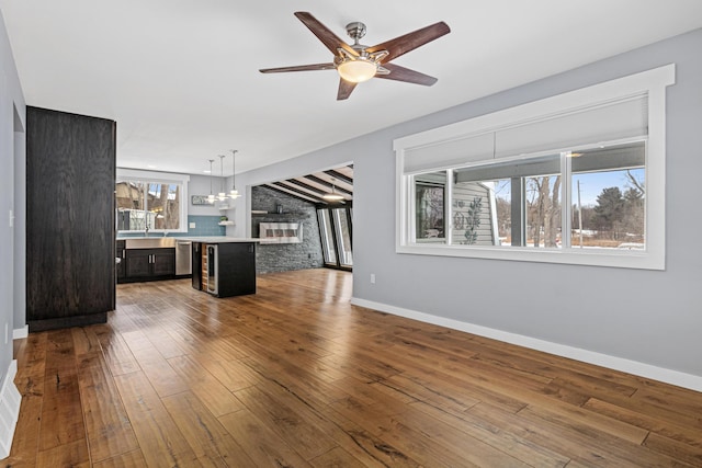 unfurnished living room featuring ceiling fan, wood-type flooring, and a fireplace