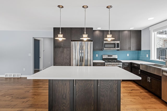 kitchen with a kitchen island, appliances with stainless steel finishes, sink, backsplash, and dark brown cabinets