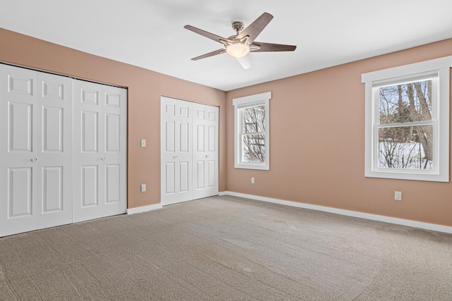 unfurnished bedroom with multiple closets, carpet floors, and ceiling fan