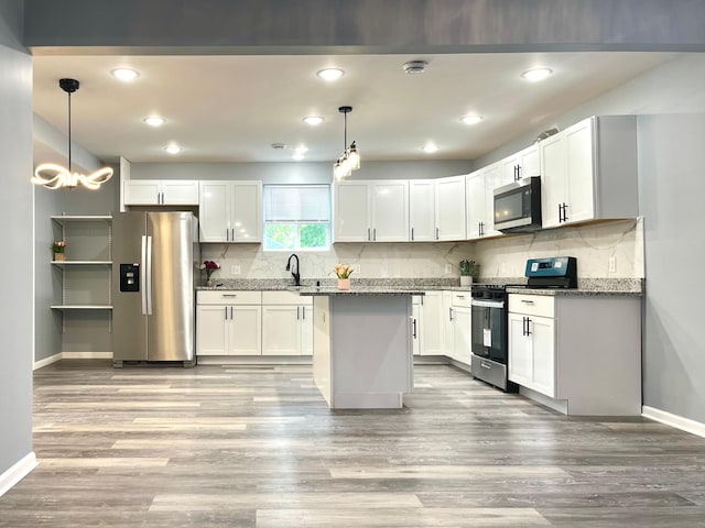 kitchen featuring white cabinets, pendant lighting, stainless steel appliances, and dark stone countertops