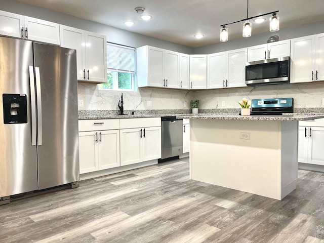 kitchen featuring a kitchen island, white cabinetry, hanging light fixtures, and appliances with stainless steel finishes