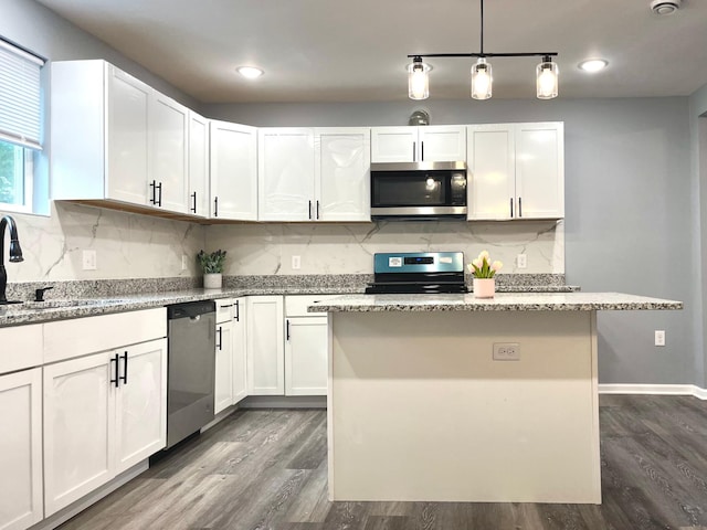 kitchen with stainless steel appliances, dark wood-type flooring, sink, a center island, and white cabinetry