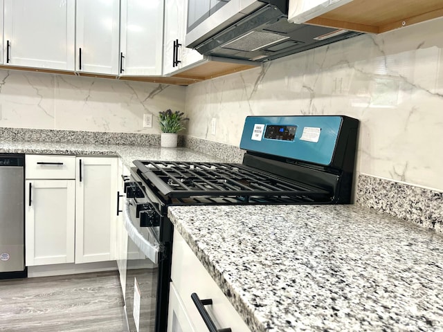 kitchen with white cabinets, light stone counters, light wood-type flooring, and stainless steel appliances