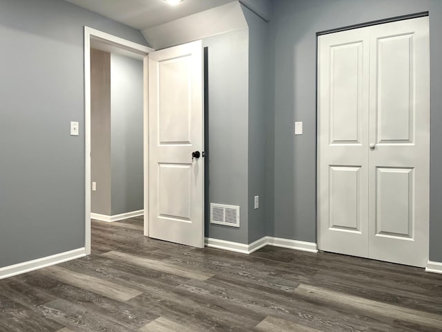 unfurnished bedroom with a closet and dark wood-type flooring