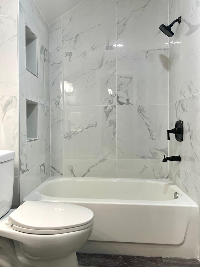 bathroom with toilet and tiled shower / bath