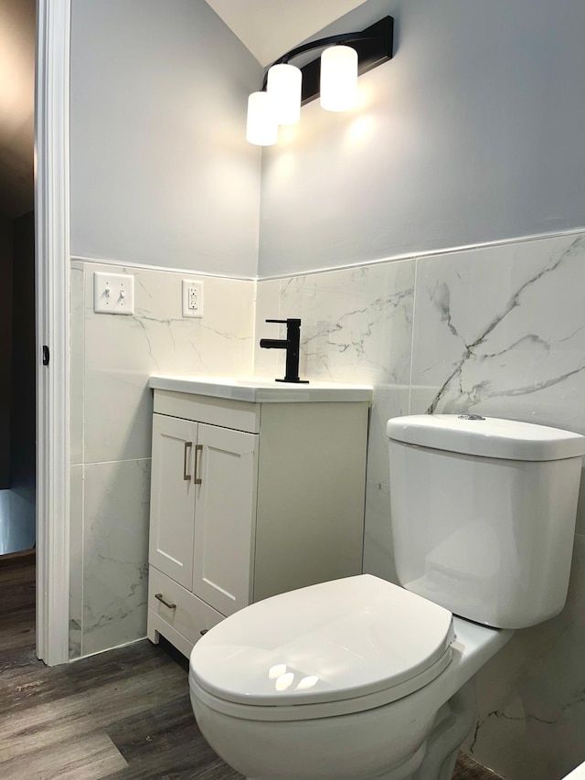 bathroom with vanity, toilet, wood-type flooring, and tile walls