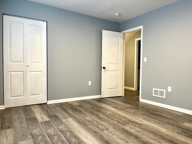 unfurnished bedroom featuring a closet and dark wood-type flooring