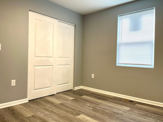 unfurnished bedroom featuring dark hardwood / wood-style flooring and a closet