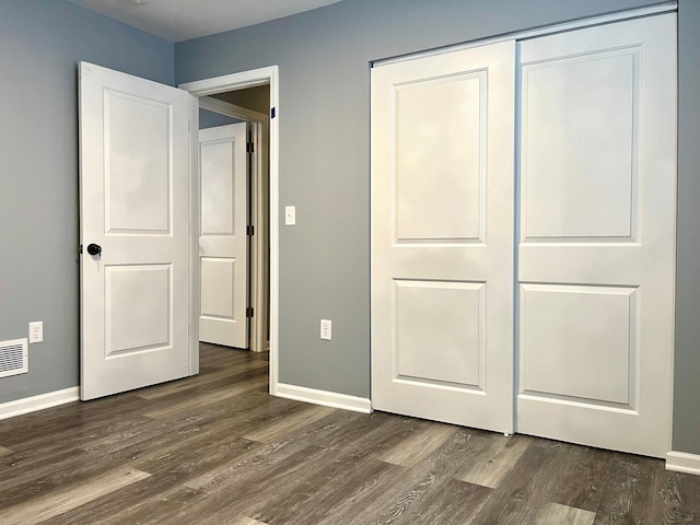 unfurnished bedroom with dark wood-type flooring and a closet