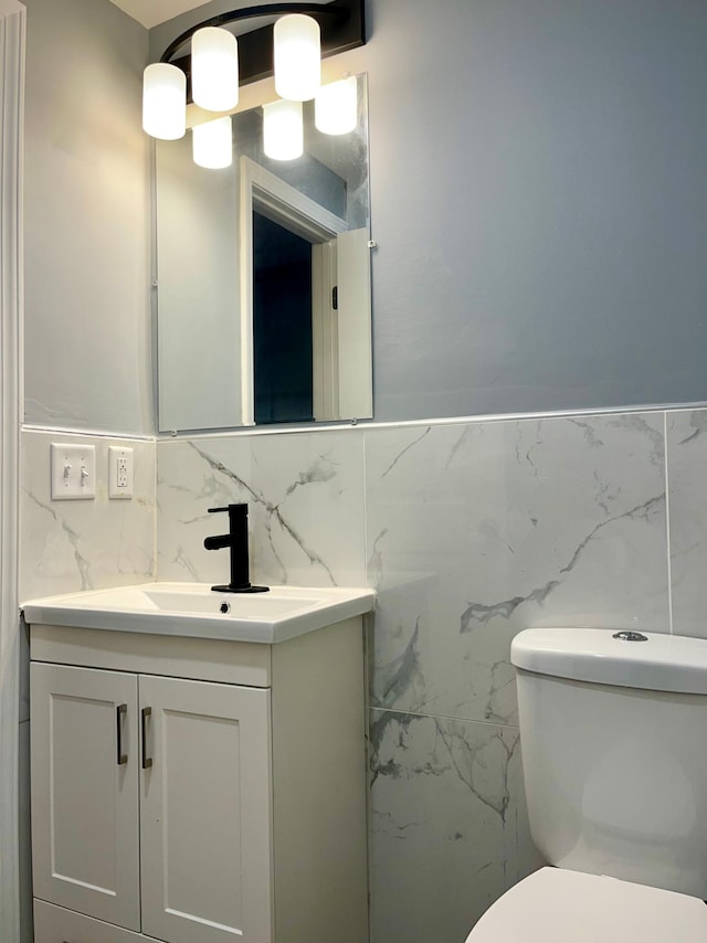 bathroom with vanity, tile walls, and toilet