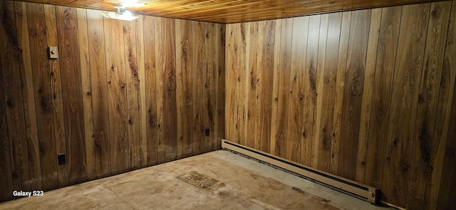 basement featuring wood ceiling, wooden walls, and a baseboard heating unit