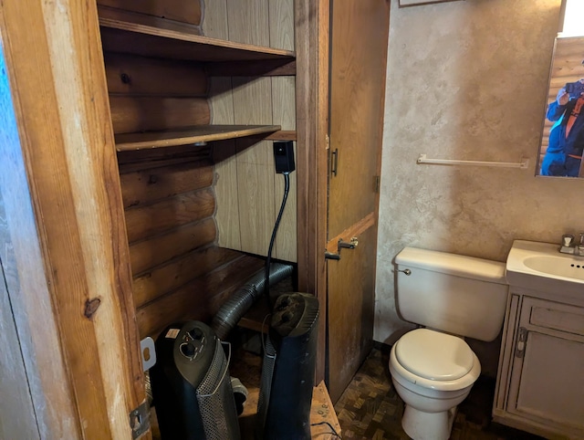 bathroom featuring parquet flooring, vanity, and toilet