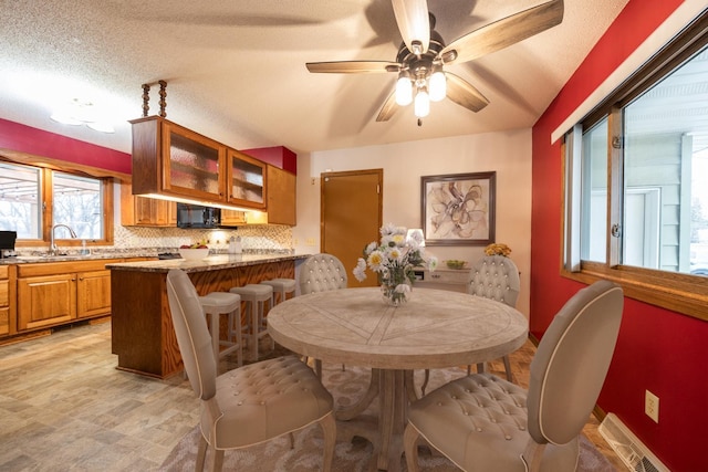 dining space featuring light hardwood / wood-style floors, sink, and a textured ceiling