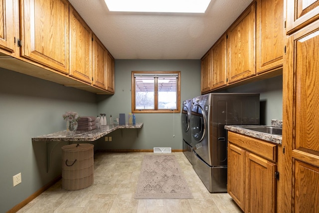 washroom with cabinets, a textured ceiling, washing machine and dryer, and sink