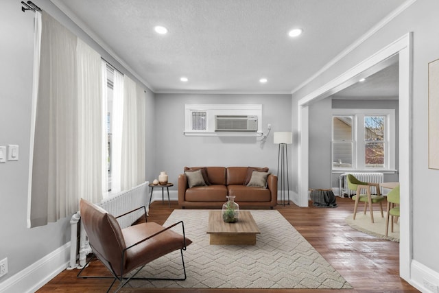 living room featuring wood-type flooring, a textured ceiling, crown molding, and radiator heating unit