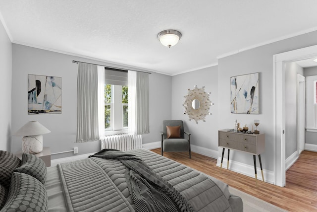 bedroom featuring crown molding, wood-type flooring, and radiator heating unit