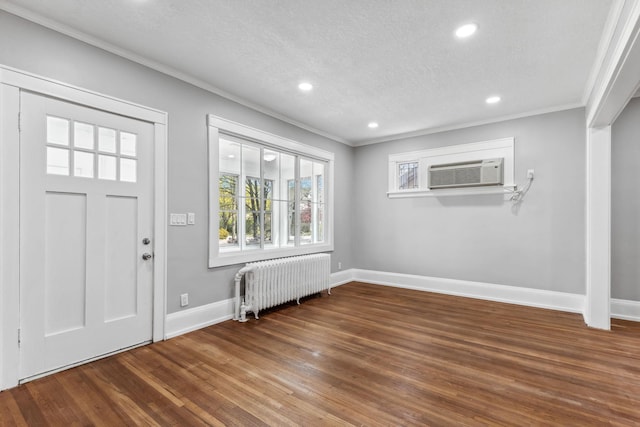 entrance foyer featuring radiator heating unit, a textured ceiling, ornamental molding, and dark wood-type flooring