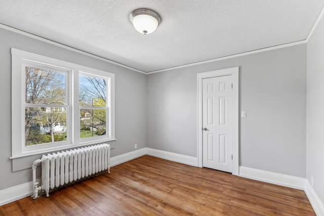 spare room featuring a textured ceiling, hardwood / wood-style flooring, radiator, and crown molding