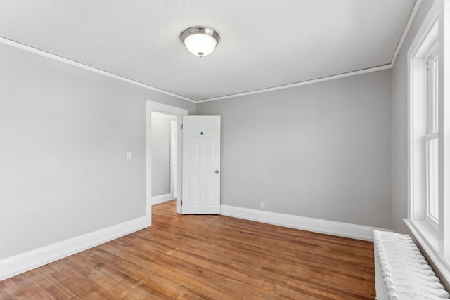 unfurnished room featuring hardwood / wood-style floors, ornamental molding, and radiator