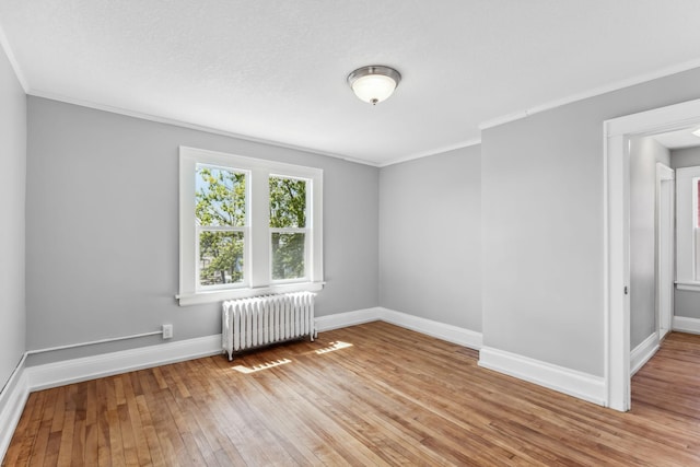 unfurnished room featuring radiator heating unit, light hardwood / wood-style flooring, and crown molding