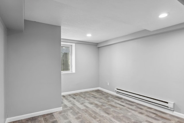 basement with light hardwood / wood-style floors and a baseboard heating unit