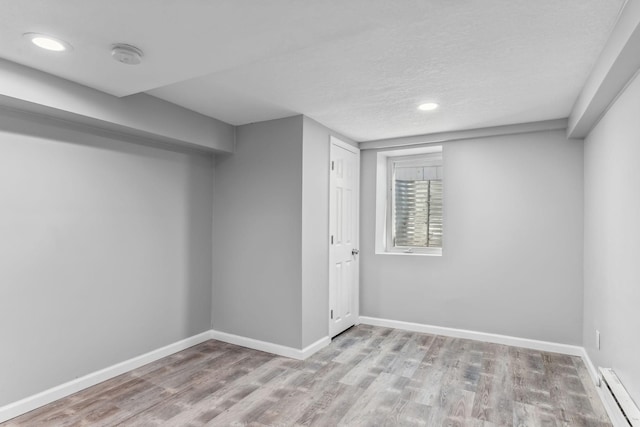 basement featuring light hardwood / wood-style floors and baseboard heating