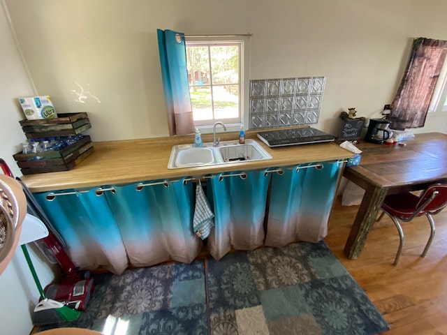 kitchen with hardwood / wood-style floors, wood counters, blue cabinetry, and sink