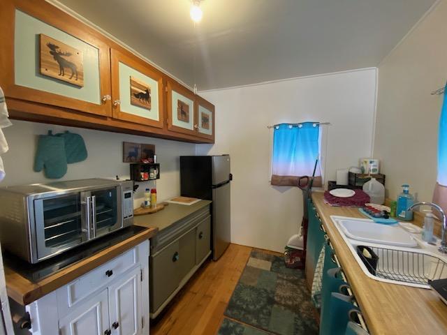 kitchen with stainless steel fridge, light hardwood / wood-style flooring, and sink