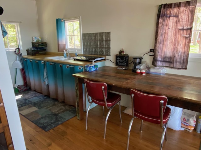 kitchen featuring butcher block countertops, sink, a healthy amount of sunlight, and hardwood / wood-style flooring