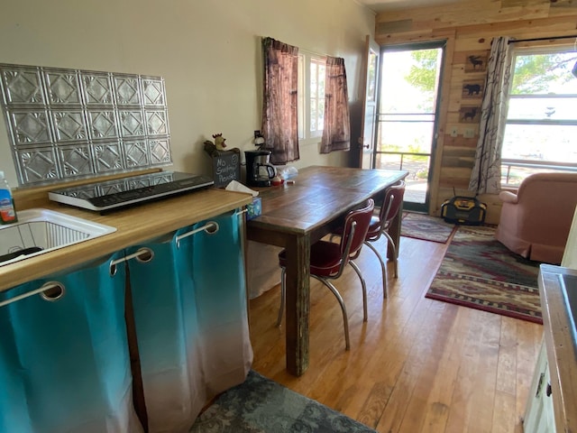 dining space with sink, light hardwood / wood-style flooring, and wood walls