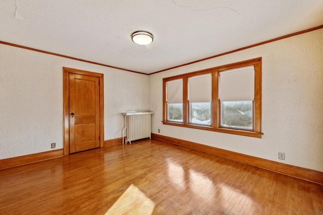 unfurnished room with radiator, light hardwood / wood-style flooring, and ornamental molding