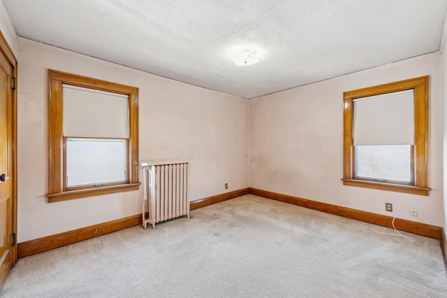 carpeted spare room with radiator and a textured ceiling