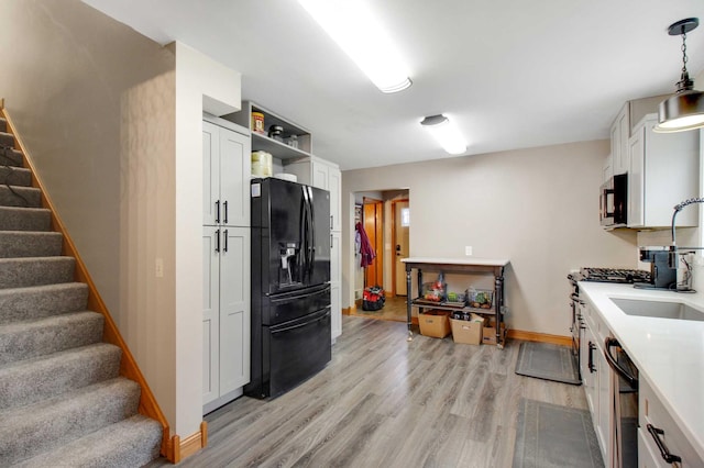 kitchen featuring white cabinets, pendant lighting, light hardwood / wood-style floors, and stainless steel appliances