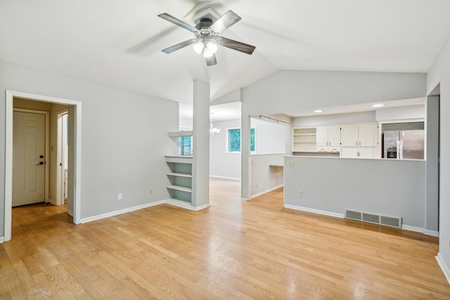 unfurnished living room featuring ceiling fan with notable chandelier, light wood-type flooring, plenty of natural light, and lofted ceiling