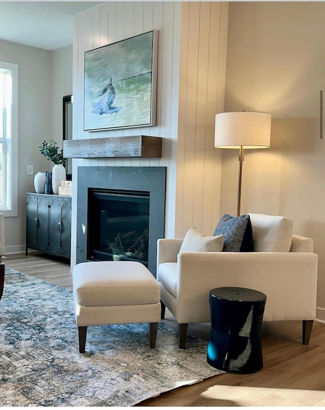 sitting room featuring light wood-type flooring, a large fireplace, and a healthy amount of sunlight