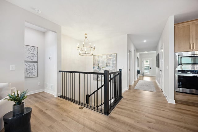 hall featuring light hardwood / wood-style flooring and a notable chandelier