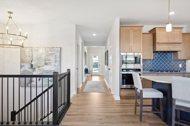 kitchen featuring decorative light fixtures, light hardwood / wood-style floors, decorative backsplash, stainless steel appliances, and a chandelier