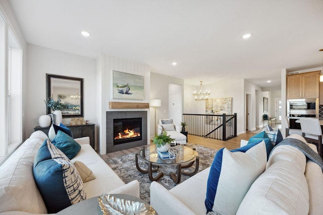 living room featuring an inviting chandelier, light hardwood / wood-style floors, a fireplace, and plenty of natural light