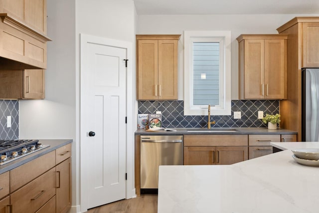 kitchen with light wood-type flooring, stainless steel appliances, backsplash, and sink