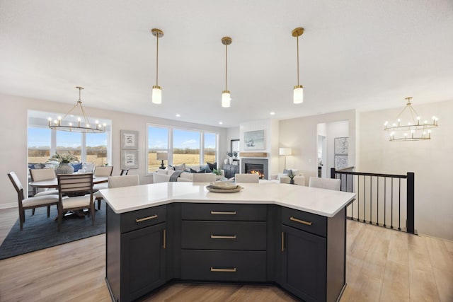 kitchen featuring hanging light fixtures, a center island, a chandelier, and light hardwood / wood-style flooring